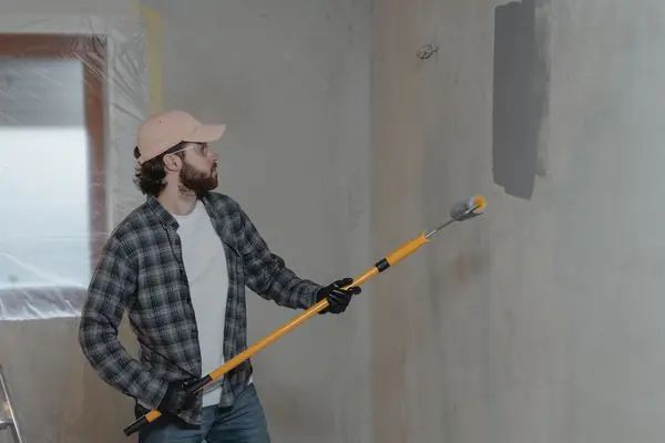 Painter rolling grey paint onto an interior wall in Allentown