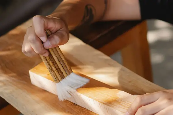 Wood being stained with a brush